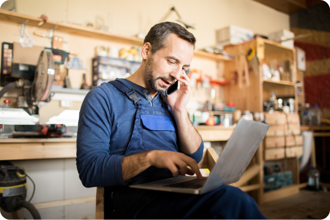Coffee shop owner ordering goods for his business online while speaking on the phone.