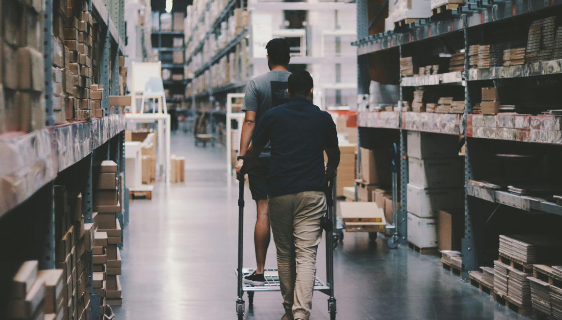 Men pushing a shopping cart around a warehouse to purchase materials and goods for their business.